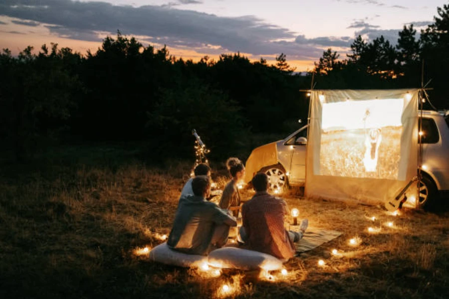 Group sitting on waterproof picnic blanket watching a movie outdoors