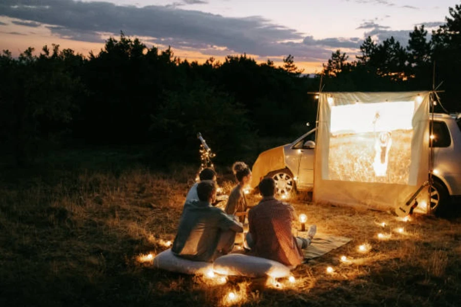 Group sitting on waterproof picnic blanket watching a movie outdoors