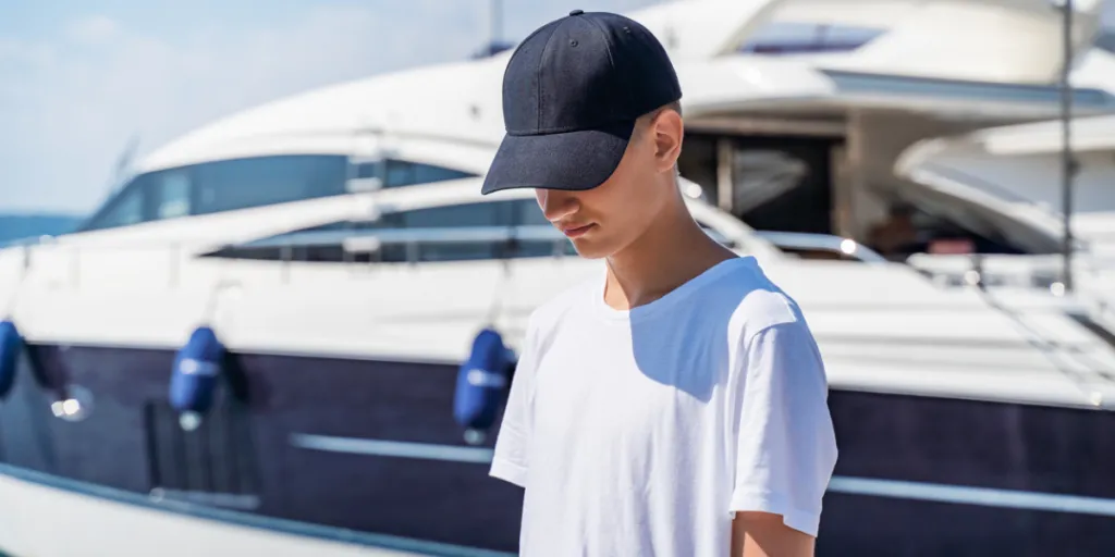 hamdsome boy wearing baseball cap standing by sea