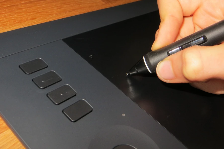 Hand using a black stylus on a graphic tablet