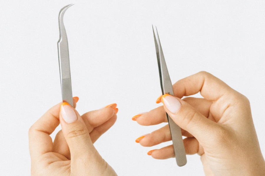 Hands holding two tweezers on a white background
