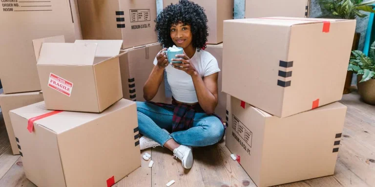 Lady sitting among a pile of cardboard boxes