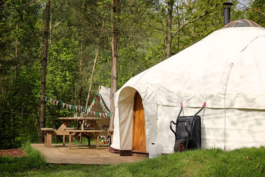 Large white canvas yurt with wooden door in summer