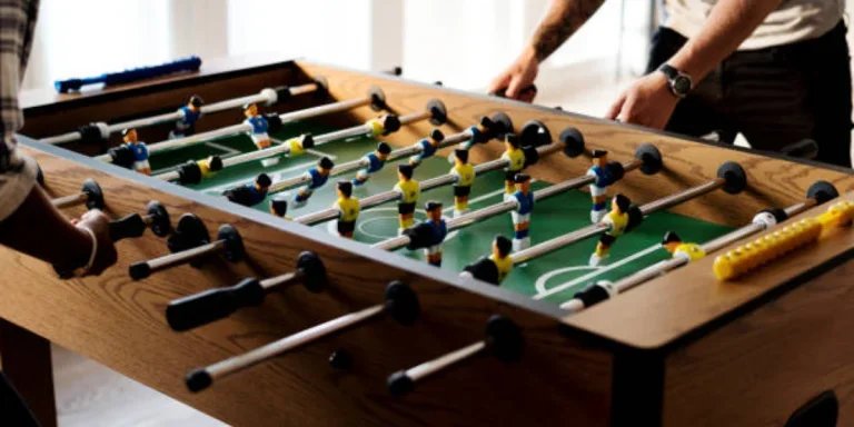 Man and woman playing with wooden foosball table indoors