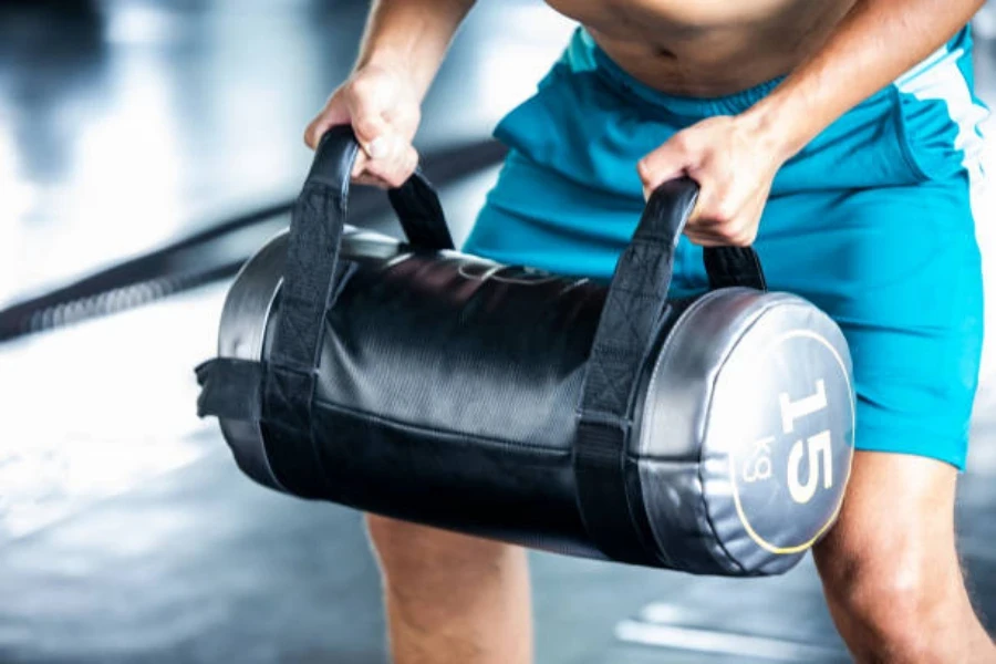 Man doing a bicep curl using a black weighted sandbag