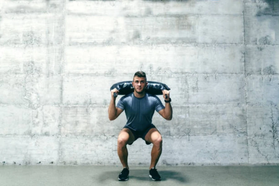 Man doing a squat using a black Bulgarian bag