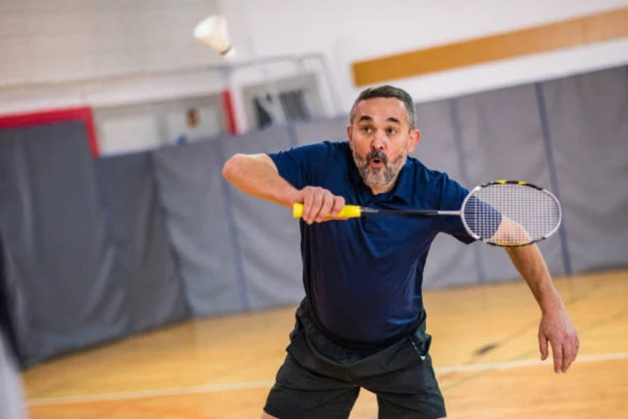 Homme frappant un revers avec une raquette de badminton frontale