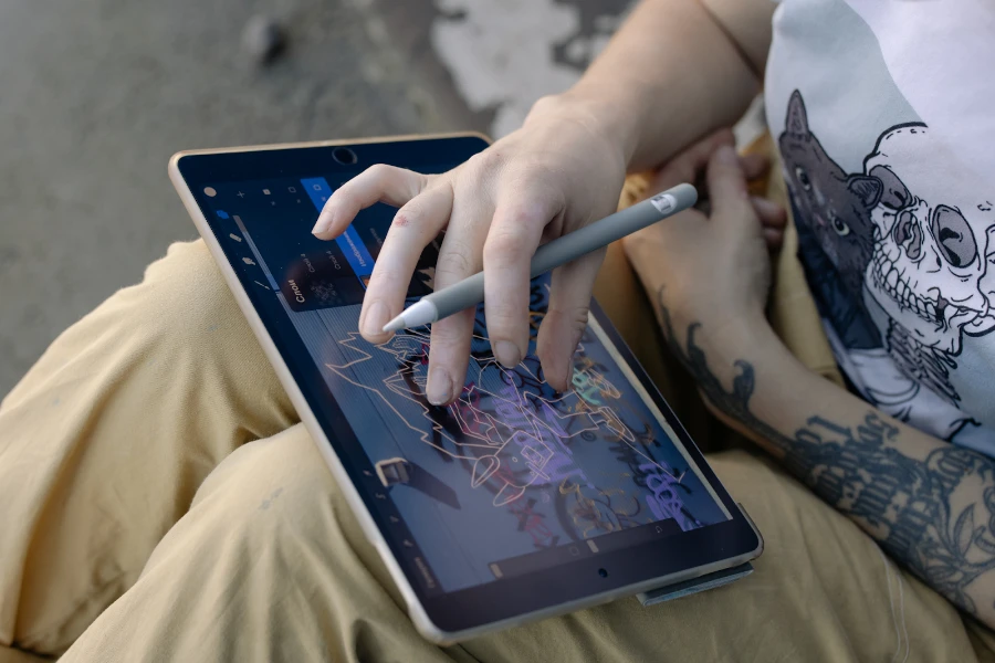 Man holding a gray stylus pen while using a tablet