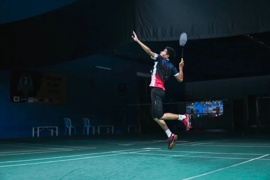 Man jumping in the air to hit a shuttlecock indoors