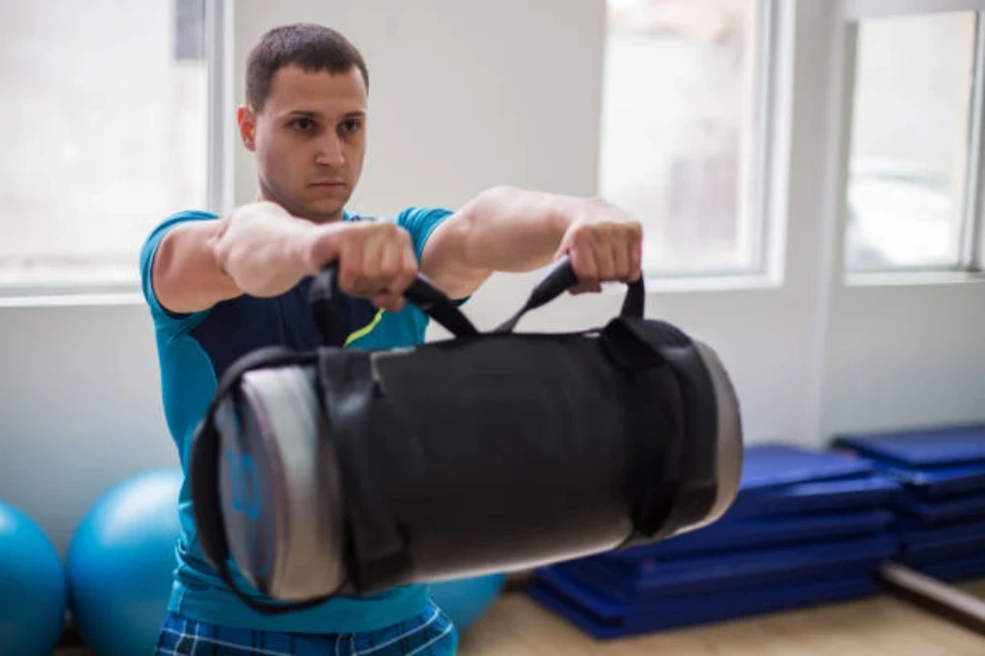 Man lifting black weighted power bag in front of body