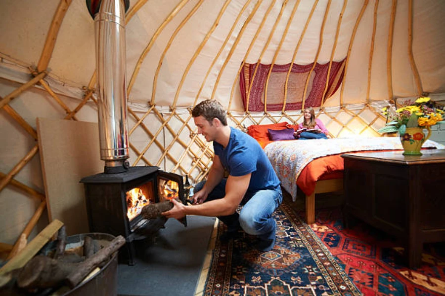 Man putting wood in fire inside a yurt tent