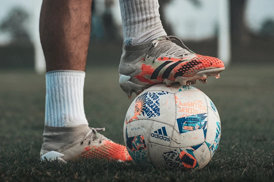 Uomo che calpesta un pallone da calcio con le tacchette