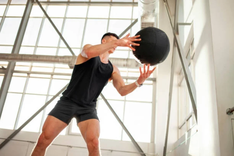 Man throwing a weighted exercise ball against the wall