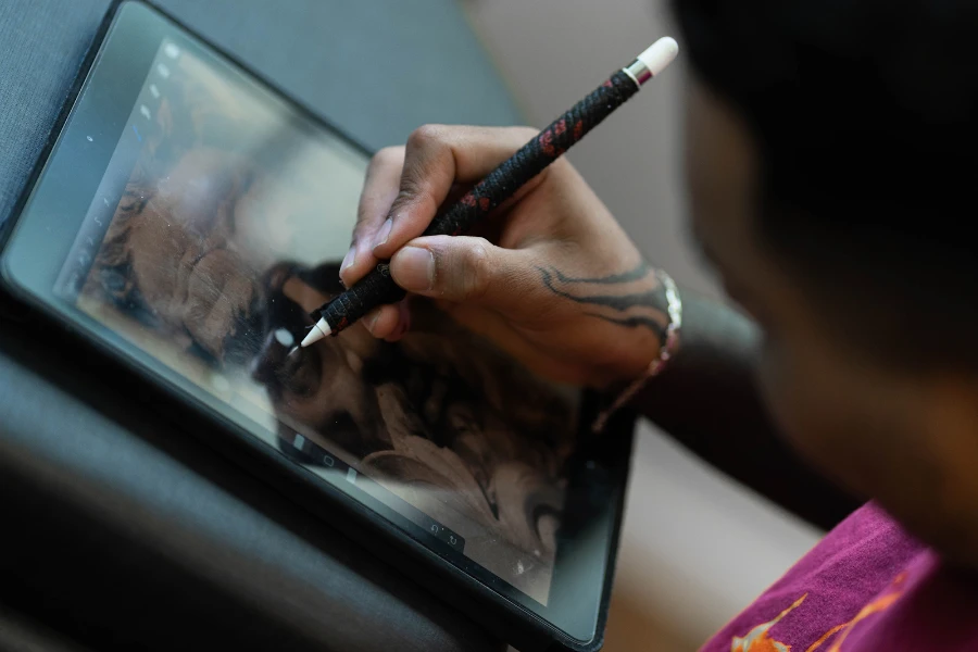 Man using a black stylus to draw on a tablet