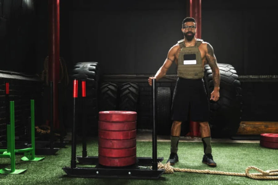 Man wearing a green weighted vest next to tires