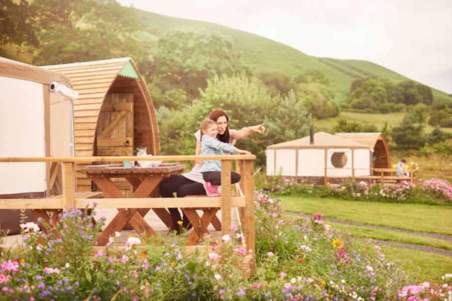 Mother and daughter sitting outside wooden framed yurt tent