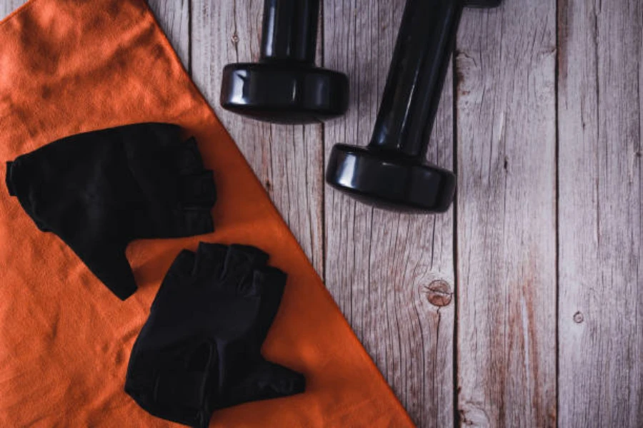 Pair of black weightlifting gloves sitting next to dumbbells