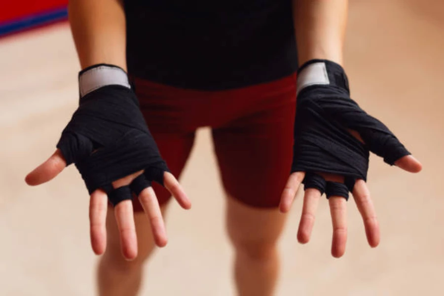 Человек, протягивающий руки, чтобы показать перчатки для тяжелой атлетики без пальцев