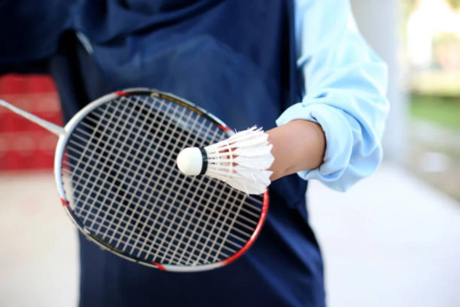 Person holding racket and shuttlecock getting ready to serve