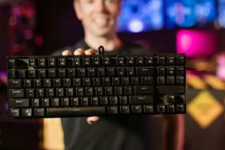 Person holding up a black membrane gaming keyboard