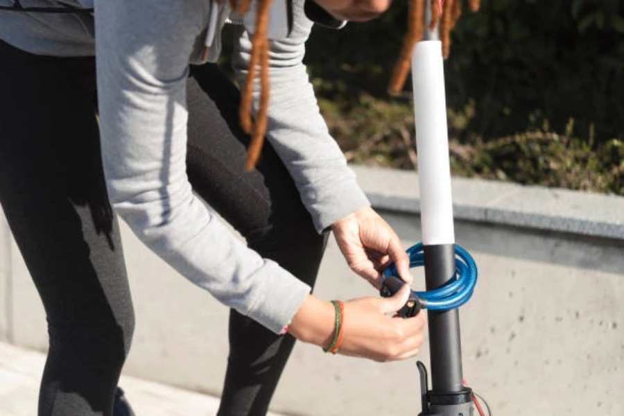 Persona poniendo un candado azul alrededor de su scooter eléctrico