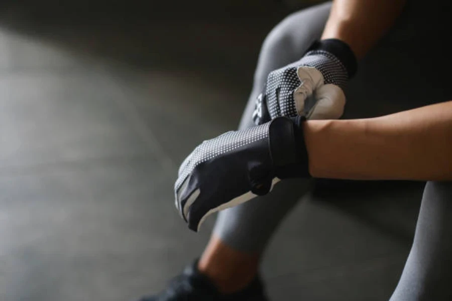 Person sitting down putting on full-fingered gym gloves