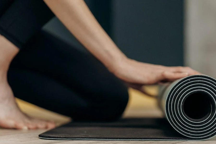 Person unfolding a black smart yoga mat