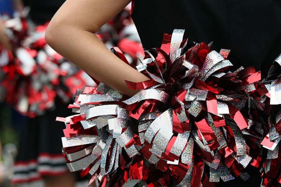 Silver and red pom poms being held by cheerleader