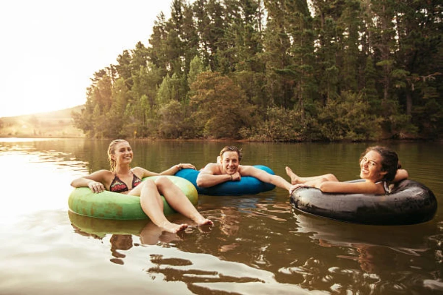 Três adultos usando anéis de natação para flutuar no lago