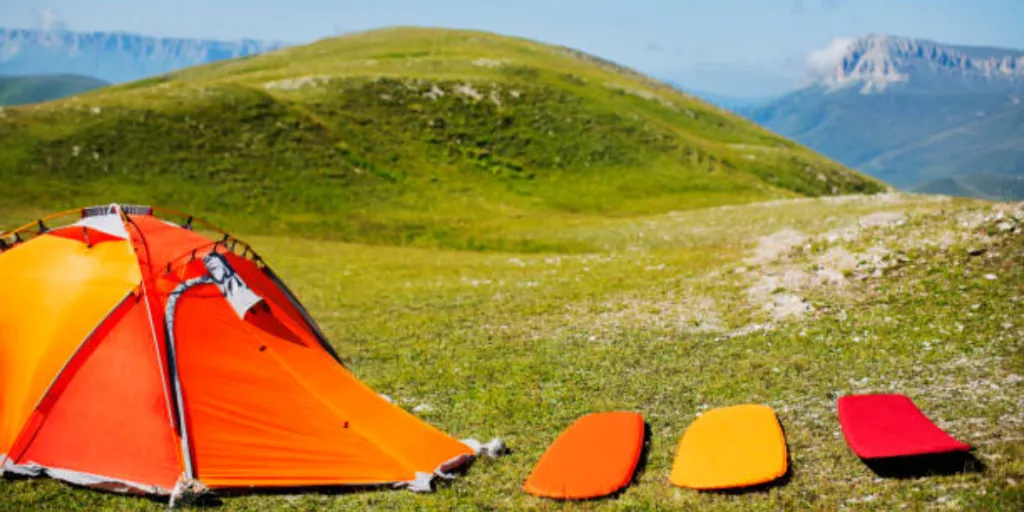 Three colorful camping mats lined up next to tent