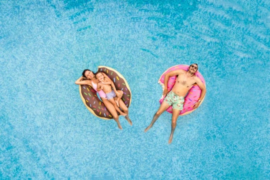 Two adults floating in different colored donut swimming rings