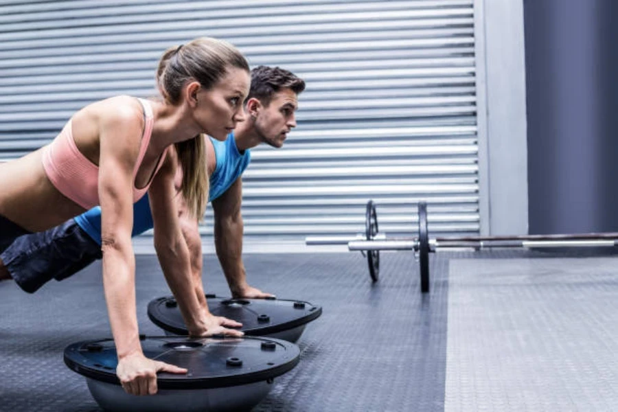 Two adults using bosu balls for upright plank exercise