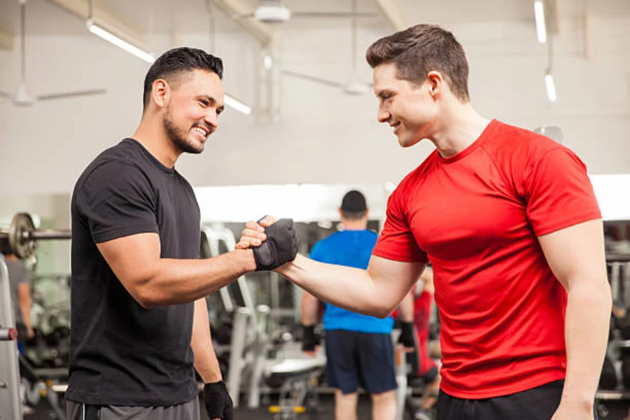 Two men greeting each other in gym wearing black gloves