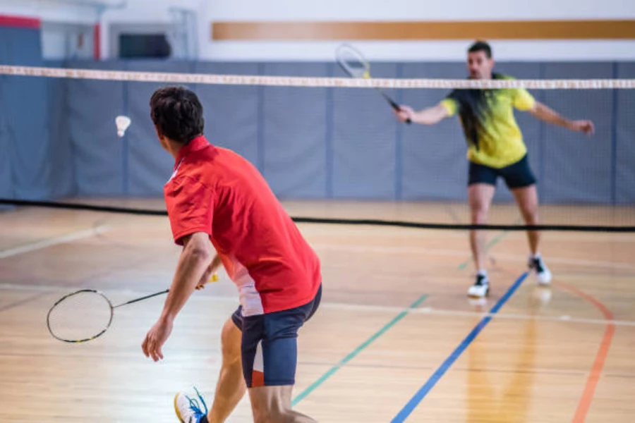Two men playing badminton on an indoor court