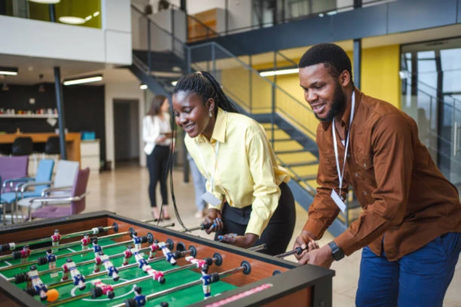 Two people using a foosball table as a team