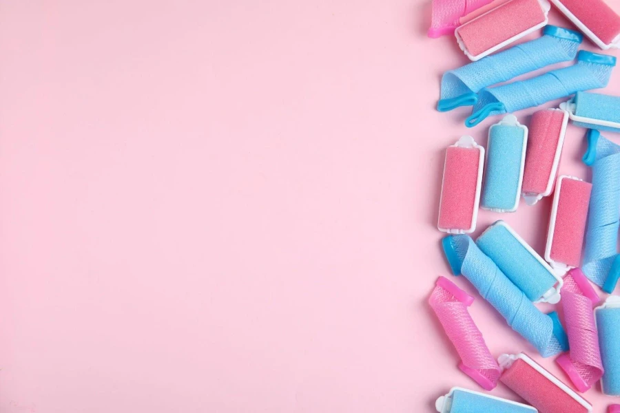 Various pink and blue foam curlers on a pink background