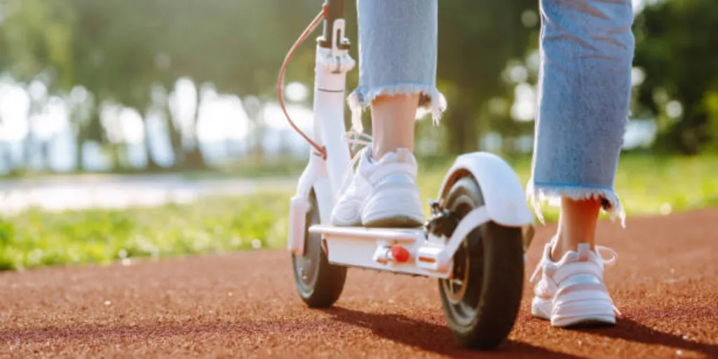 White electric scooter stopped on orange gravel in a park