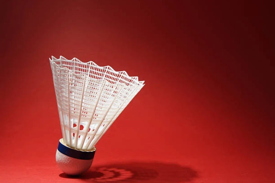 White nylon badminton shuttlecock against a red backdrop