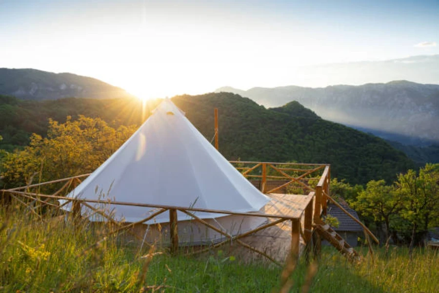 White yurt tent positioned on platform above forest