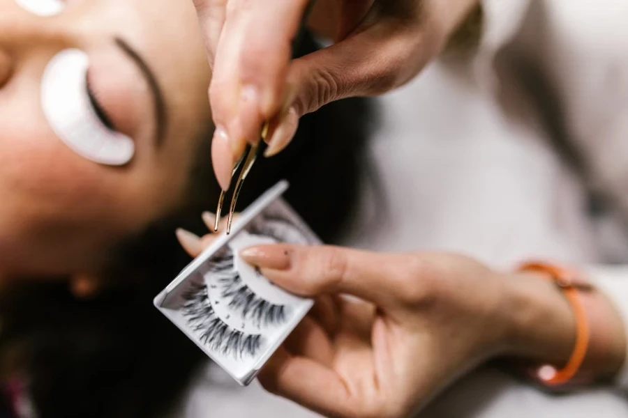 Frau wählt Wimpern aus, die sie mit einer Pinzette auswählen kann