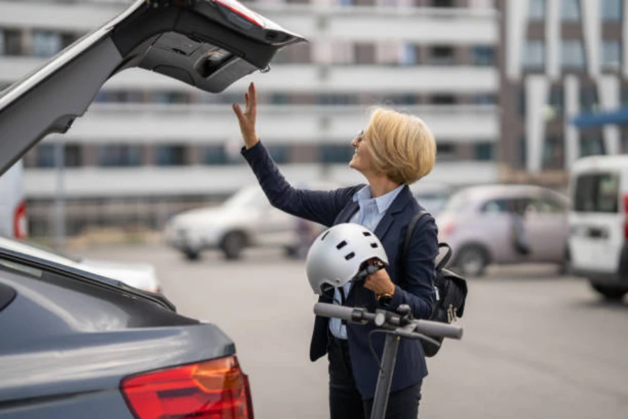 Mujer sacando scooter eléctrico de un coche con casco