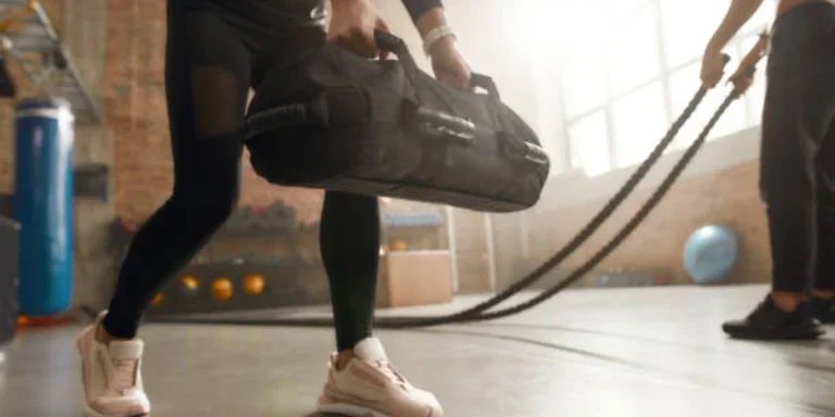 Woman holding a black power bag in a gym setting