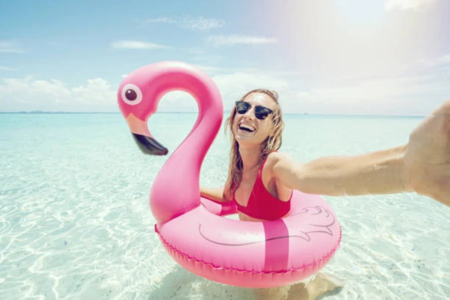 Woman in sea with a pink flamingo swimming ring