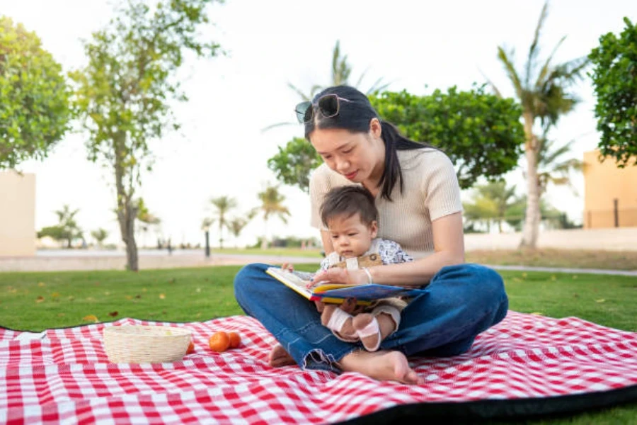 Woman sitting with baby on red checkered picnic blanket