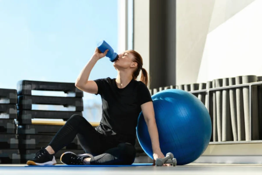 Woman taking a break next to large blue swiss ball