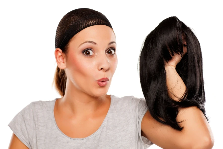 Woman wearing a wig cap and holding a wig