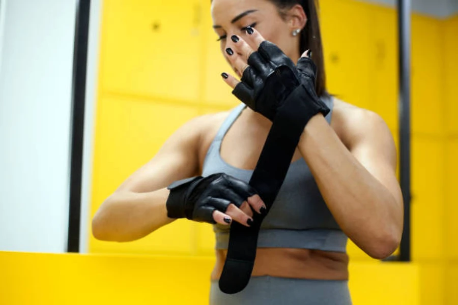 Женщина в черных тяжелоатлетических перчатках с поддержкой запястья