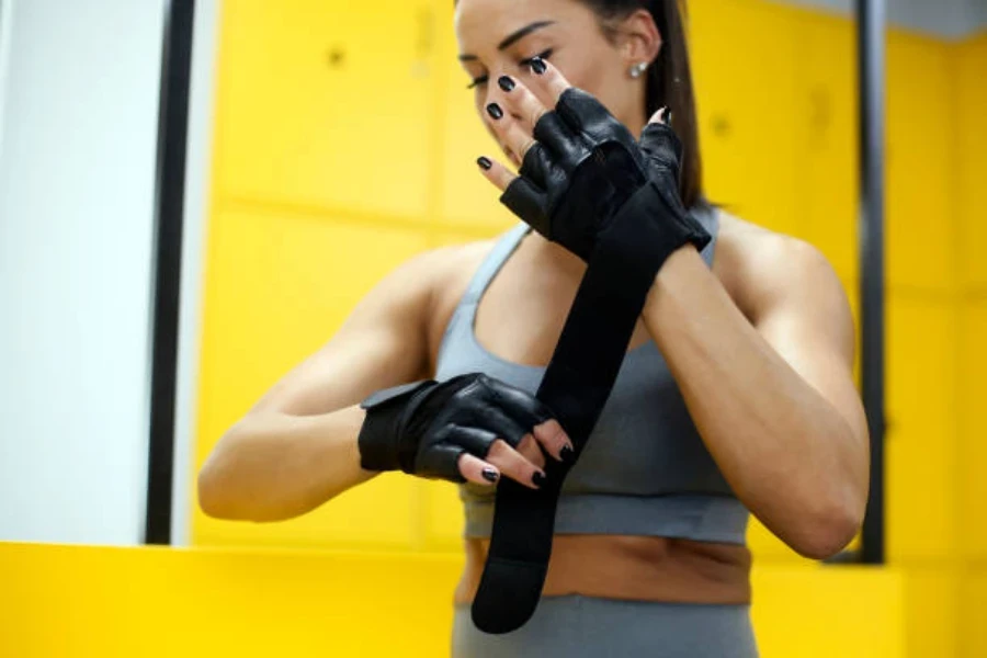 Femme portant des gants d'haltérophilie noirs avec support de poignet