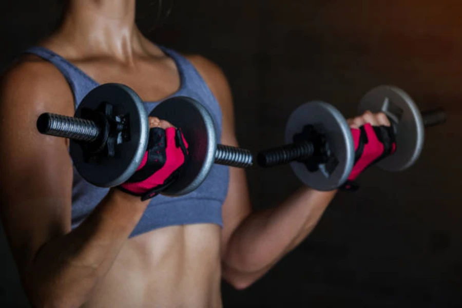 Mulher usando luvas de levantamento de peso enquanto faz rosca bíceps