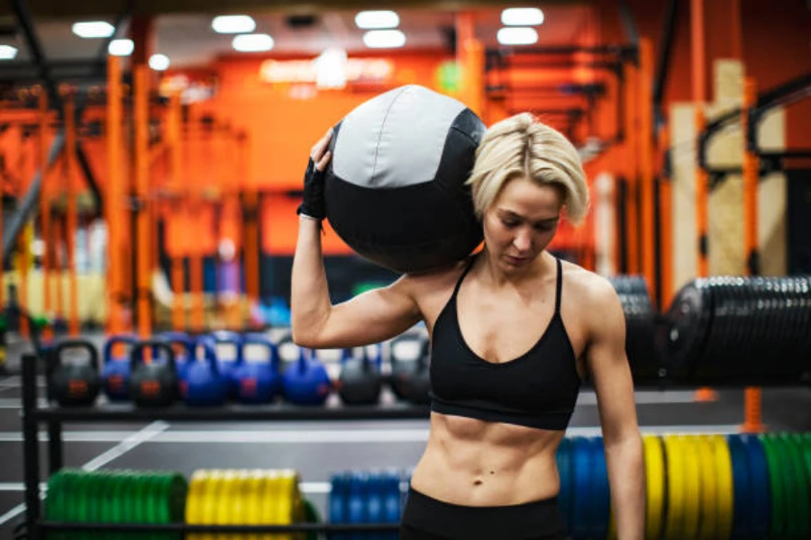 Woman with weighted power ball balanced on shoulder